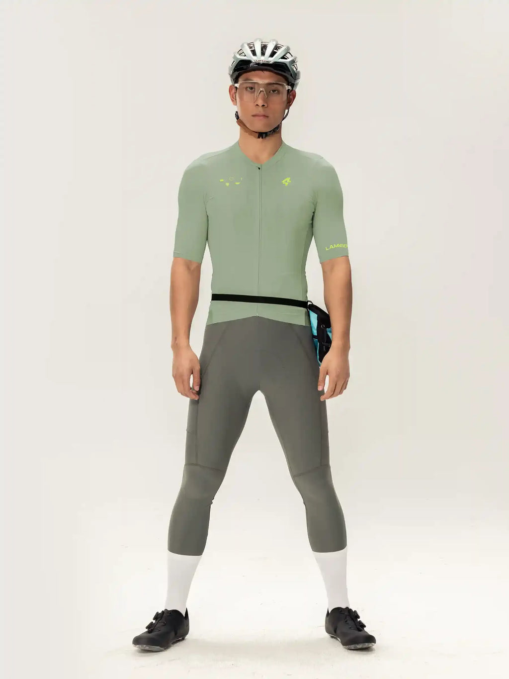 A man wearing the roam men jersey short sleeves in light green with black trim and neon yellow accents paired with gray tights
