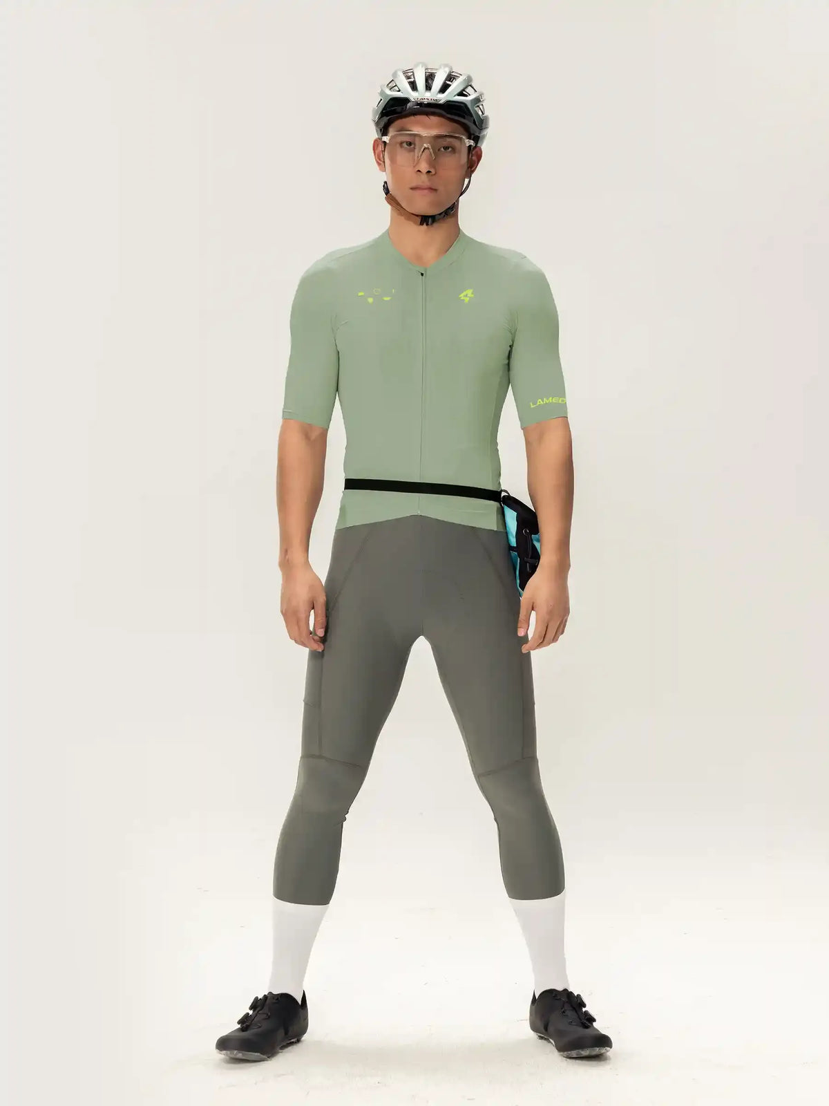 A man wearing the roam men jersey short sleeves in light green with black trim and neon yellow accents paired with gray tights