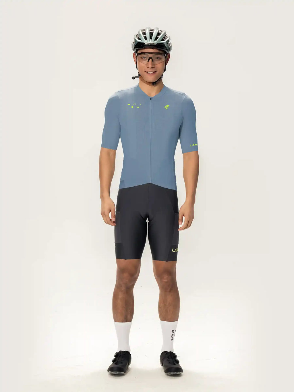A man wearing a blue roam men short sleeve cycling jersey with neon green accents and matching shorts