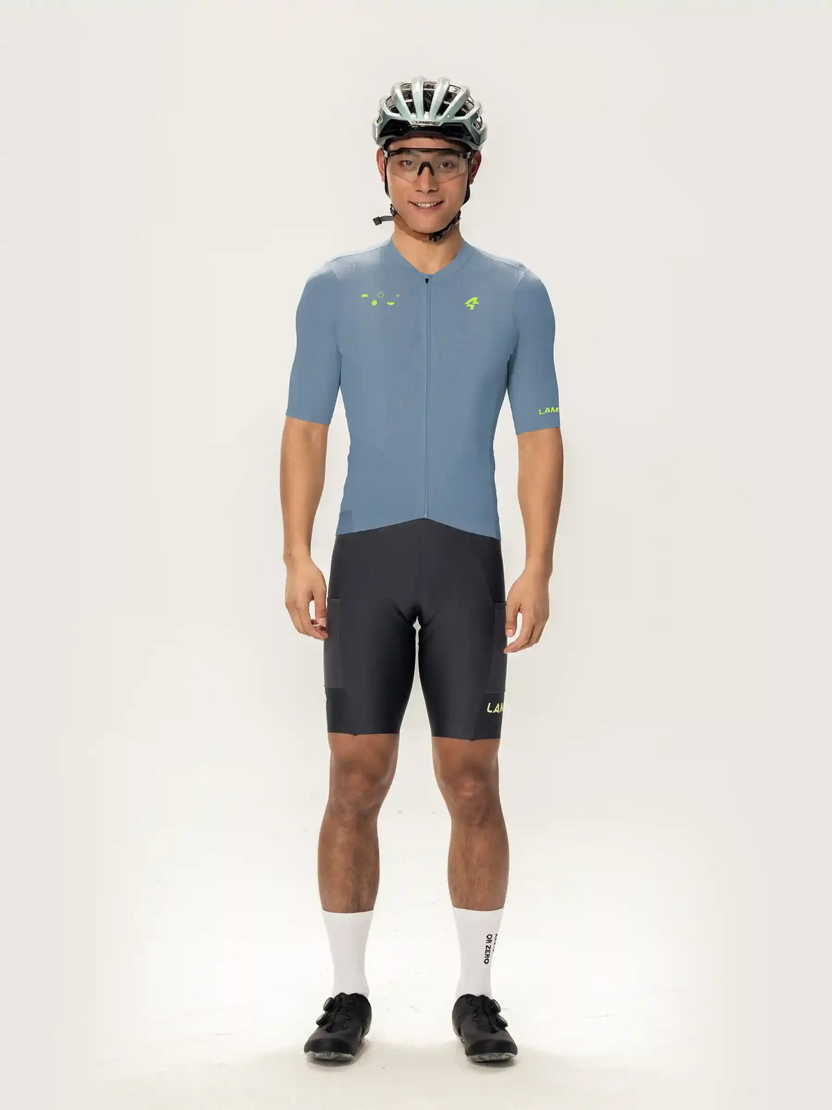 A man wearing a blue roam men short sleeve cycling jersey with neon green accents and matching shorts