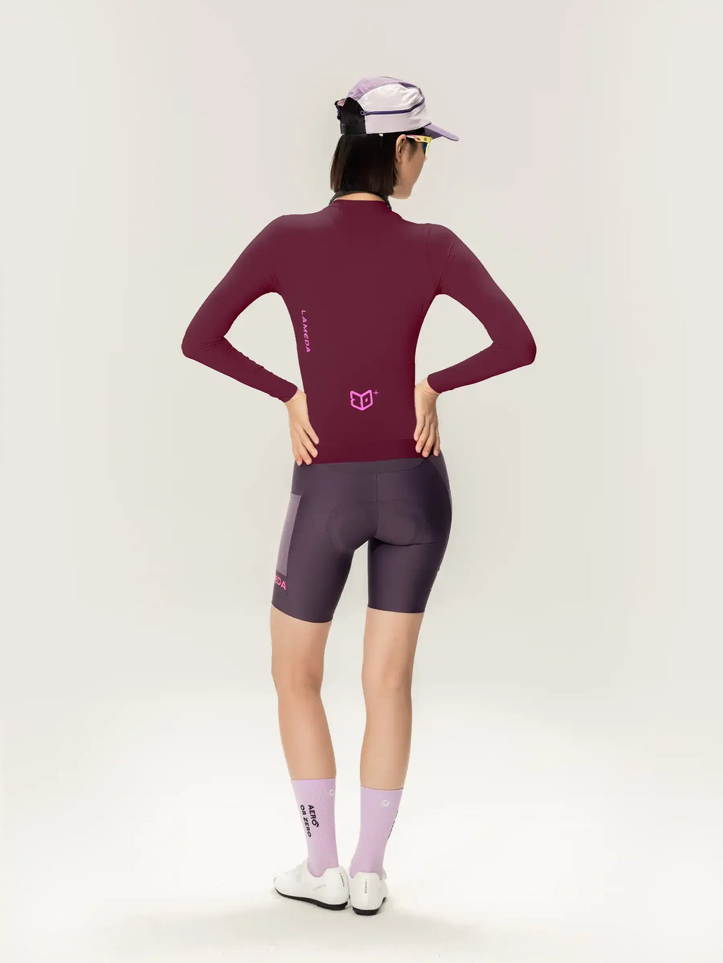 Maroon long-sleeved cycling jersey with pink logo and matching dark gray shorts for women in purple roam collection