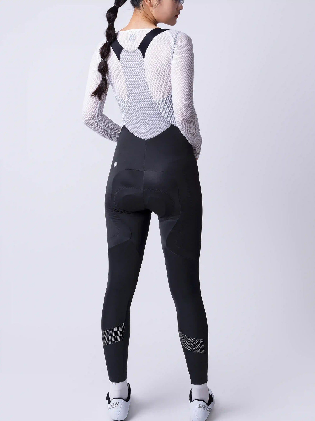Women’s black cycling bib tights with fleece-lined thighs and white perforated back panel featuring mesh inserts