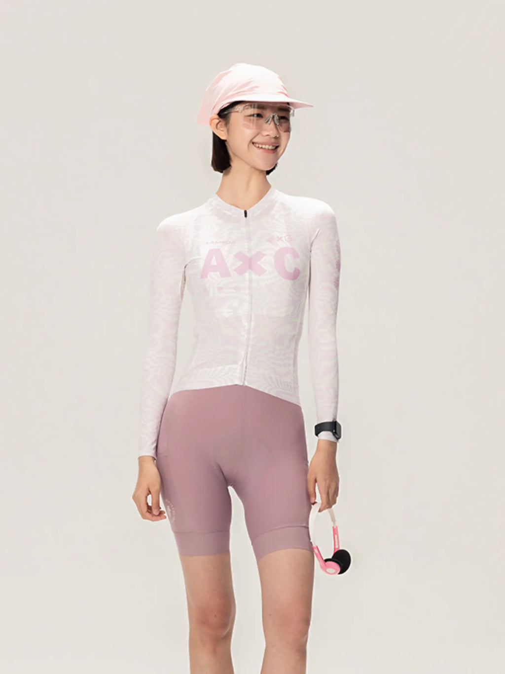 A woman wearing a white and pink lameda x australian unisex cycling jersey with mauve shorts in studio unisex cycling style