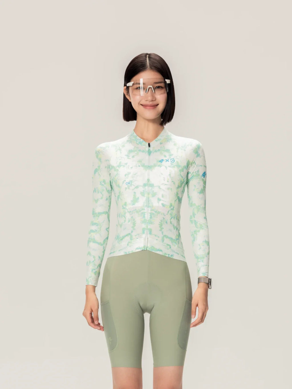 A woman wearing a light green and white abstract lameda x australian studio unisex cycling jersey with olive-green shorts