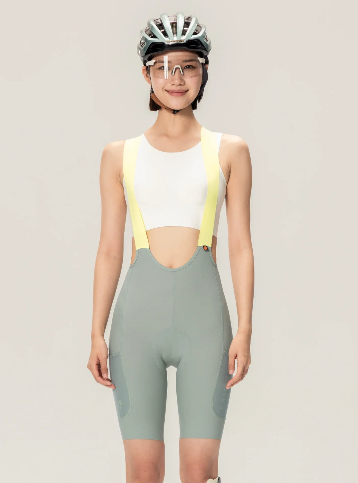 A sleek light gray cycling jersey with vibrant yellow shoulder straps paired with lameda women’s green cycling bib shorts featuring elastic interface®