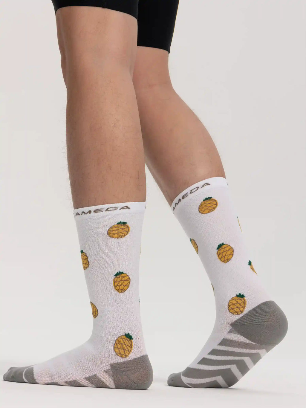 White lameda cycling socks made of fruits with yellow pineapple pattern and gray arch support accents