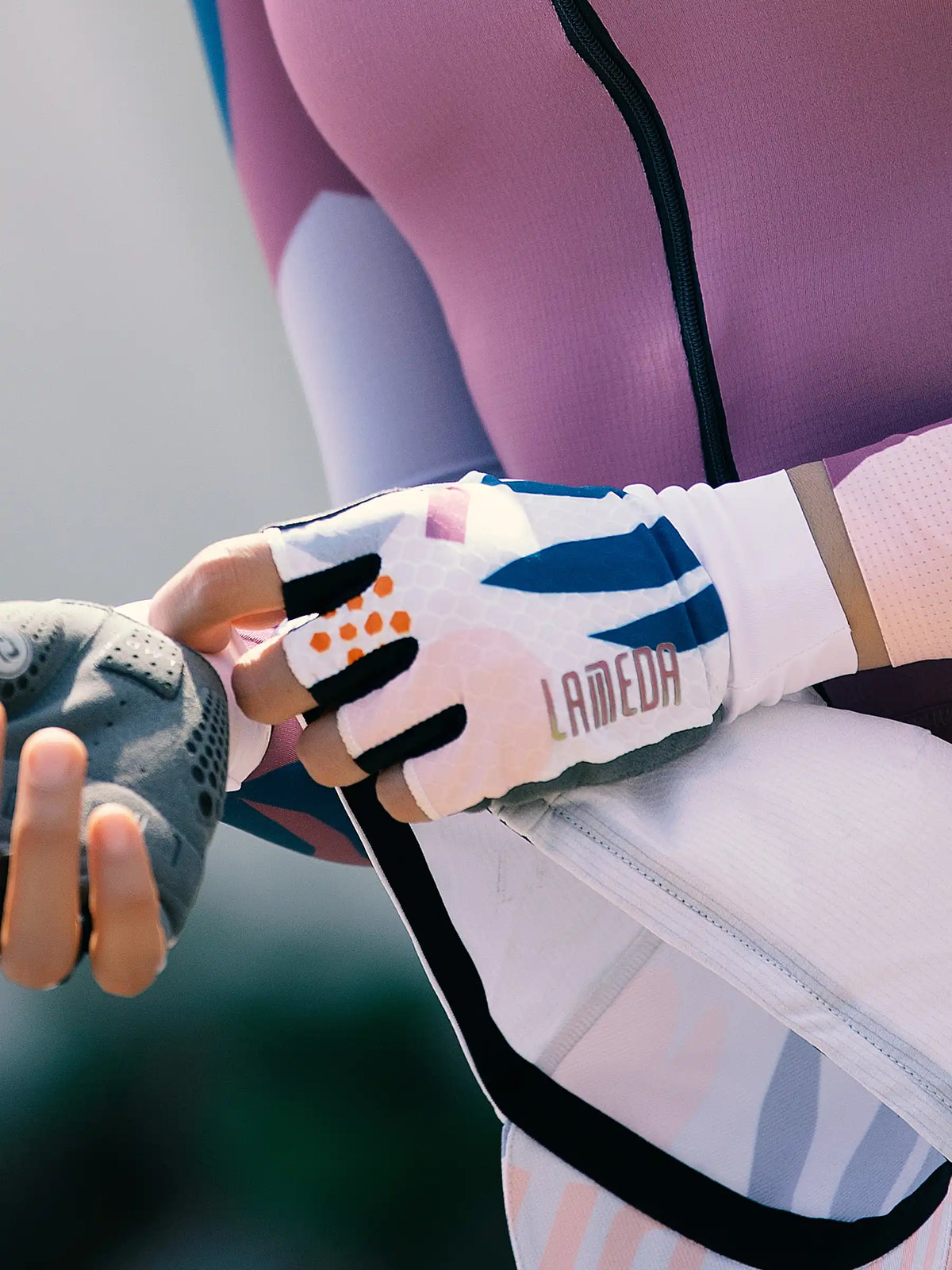 White and blue patterned lameda half-finger cycling gloves with black accents and orange dot details deliver essential grip