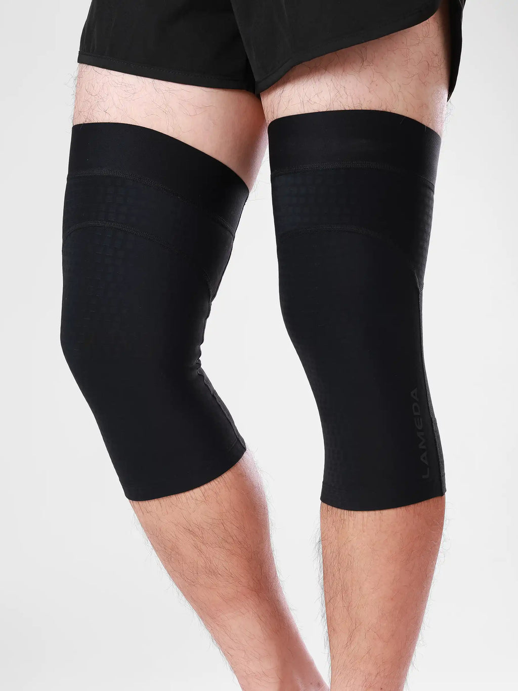 Black lameda cycling leg warmers with sleek, form-fitting design and subtle side branding for cycling leg support