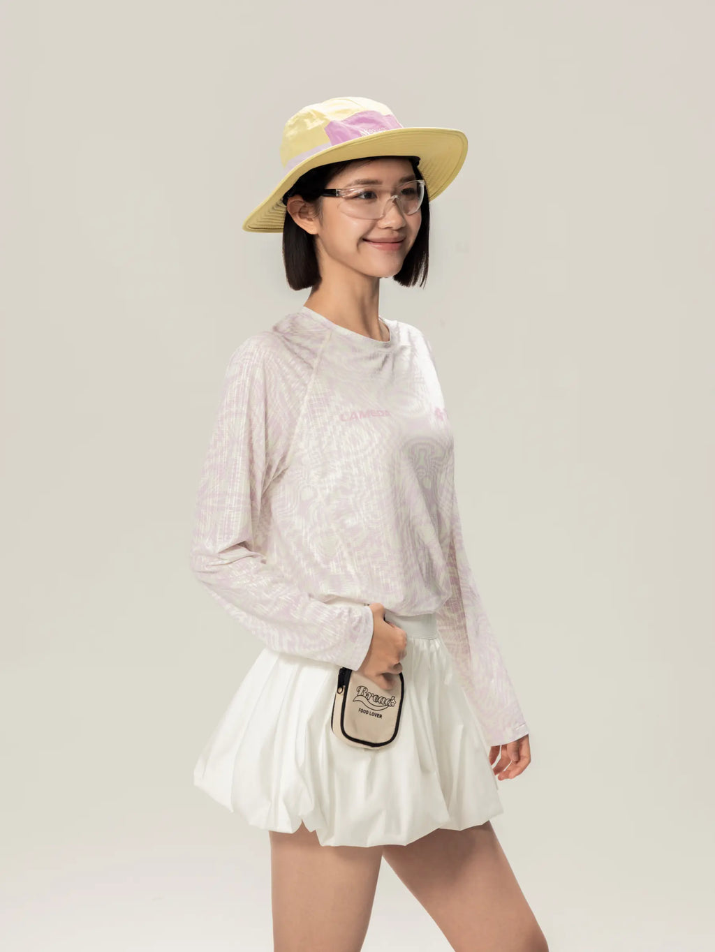 White mini crossbody bag with black trim and small logo paired with lightweight cycling long-sleeve t-shirt for daily commutes