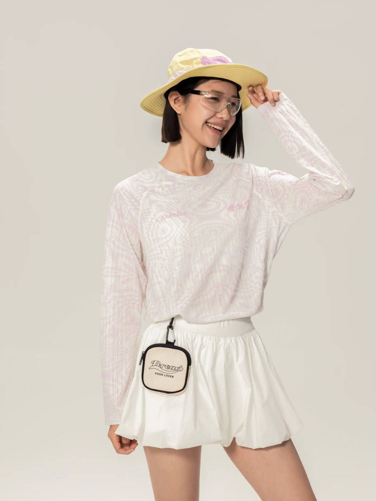 White rectangular crossbody bag with black trim and embroidered logo paired with lightweight cycling long-sleeve t-shirt for daily commutes