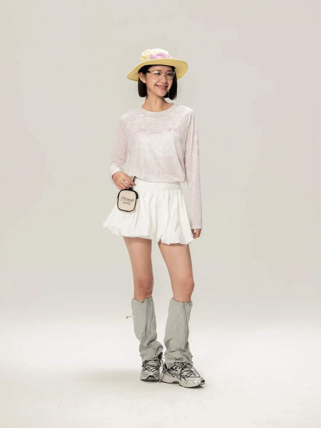 Light pink A x C unisex lightweight cycling long-sleeve t-shirt paired with a white mini skirt with flared hem and ruching