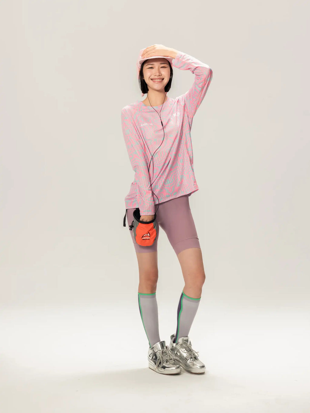 Orange compact water bottle with black strap and logo beside a pink a x c unisex lightweight cycling long-sleeve t-shirt for outdoor adventures