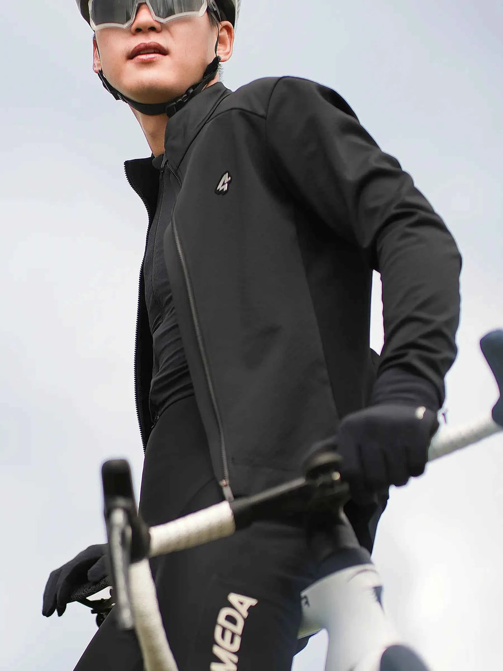 Black shield men’s cycling jacket with sleek form-fitting design and subtle chest logo for performance and style
