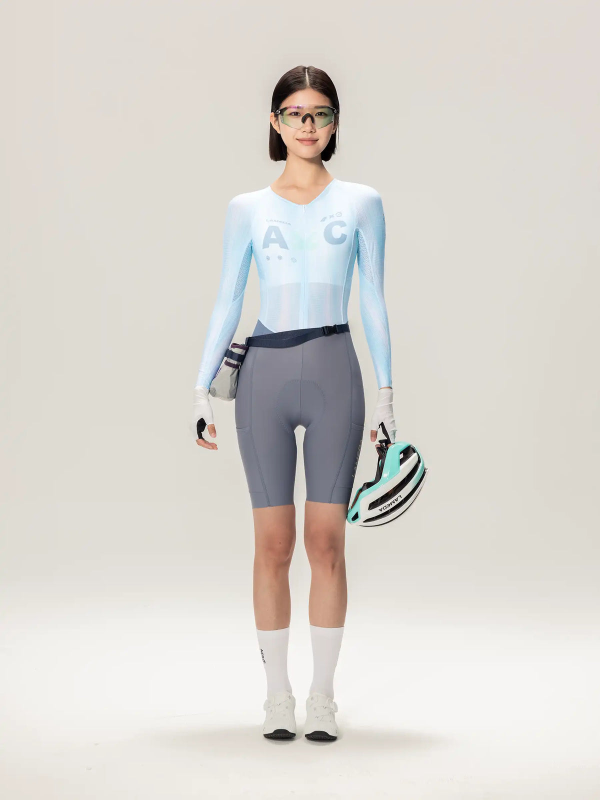 Light blue long-sleeved cycling skinsuit with subtle gradient and ac logo on chest for women cyclists