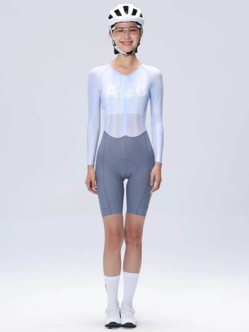 A woman wearing a white cycling helmet and light blue long-sleeved Lameda A*C women skinsuit for cycling