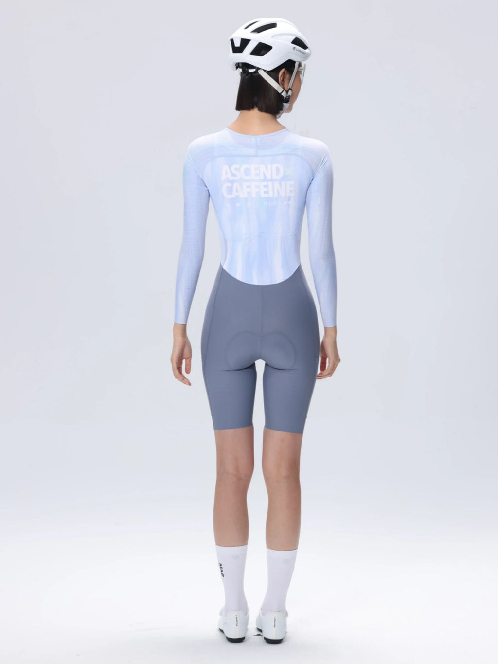 Back view of lameda ac women skinsuit long sleeves in light blue and gray with ascend caffeine print for cycling