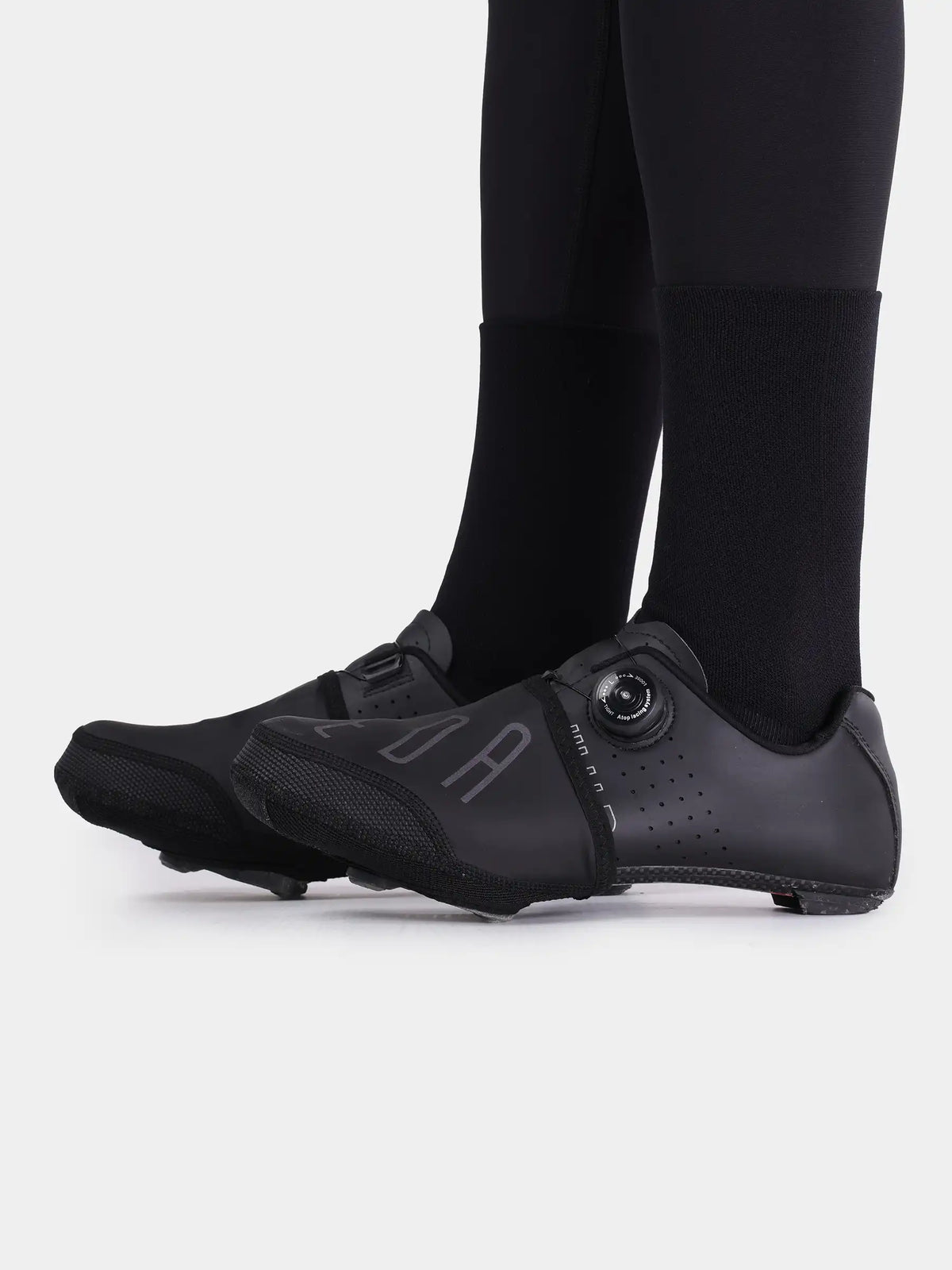 Black cycling shoe with perforated design and circular buckle featuring shoe toe caps for windproof cycling use