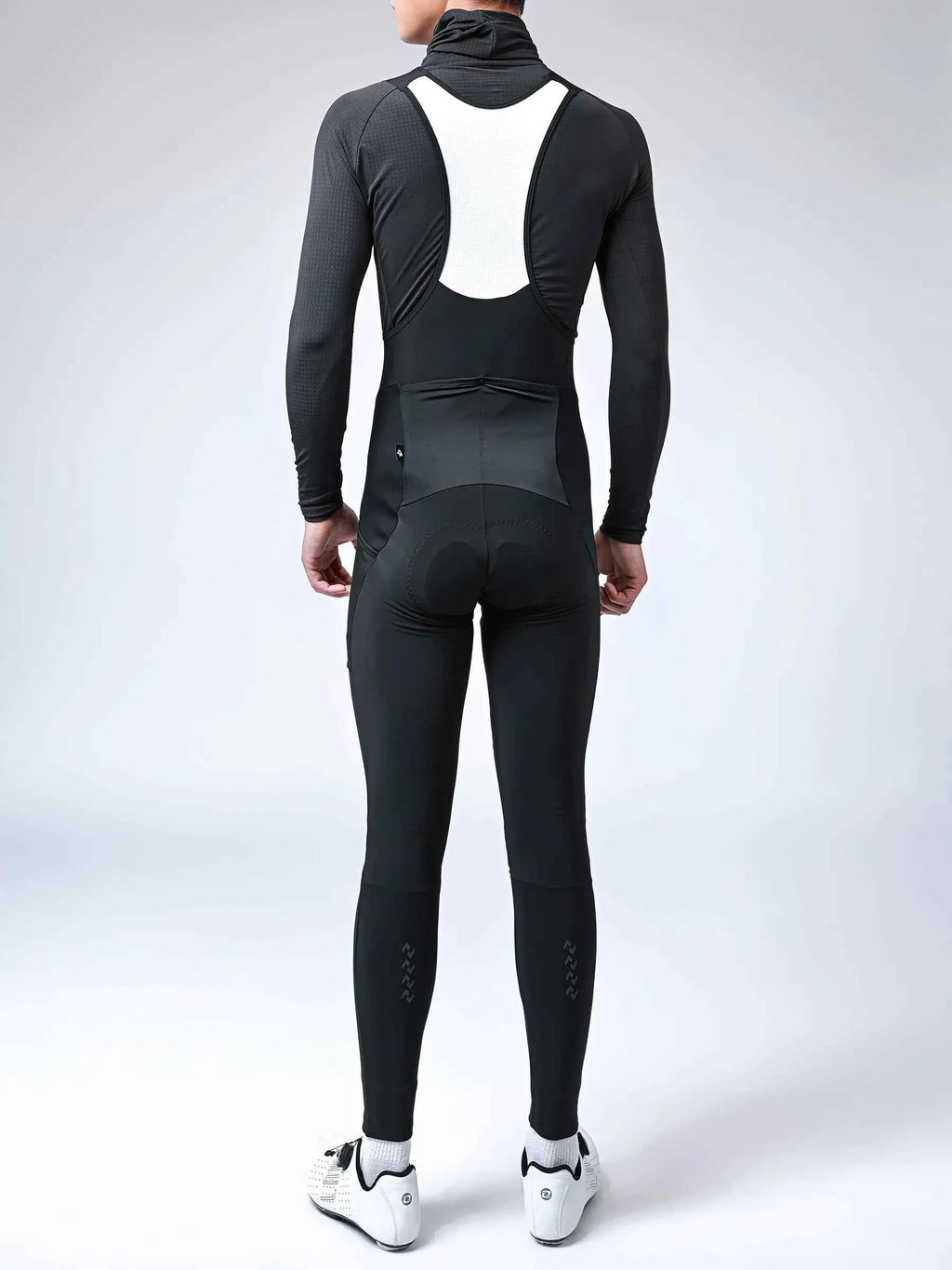 Black and white cycling jersey with high collar long sleeves and padded seat paired with thermal bib tights