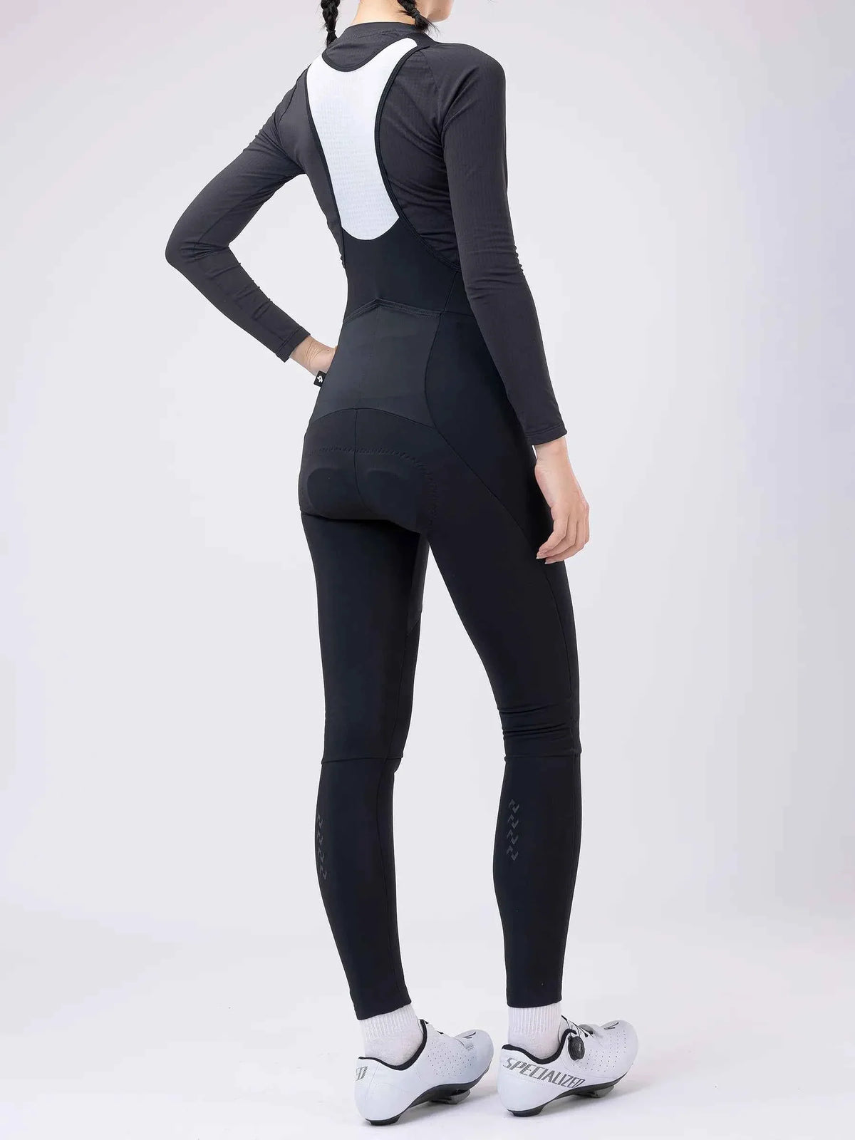 Black and white long-sleeved thermal bib tights with padded back panel seamless design and brand logo on lower leg