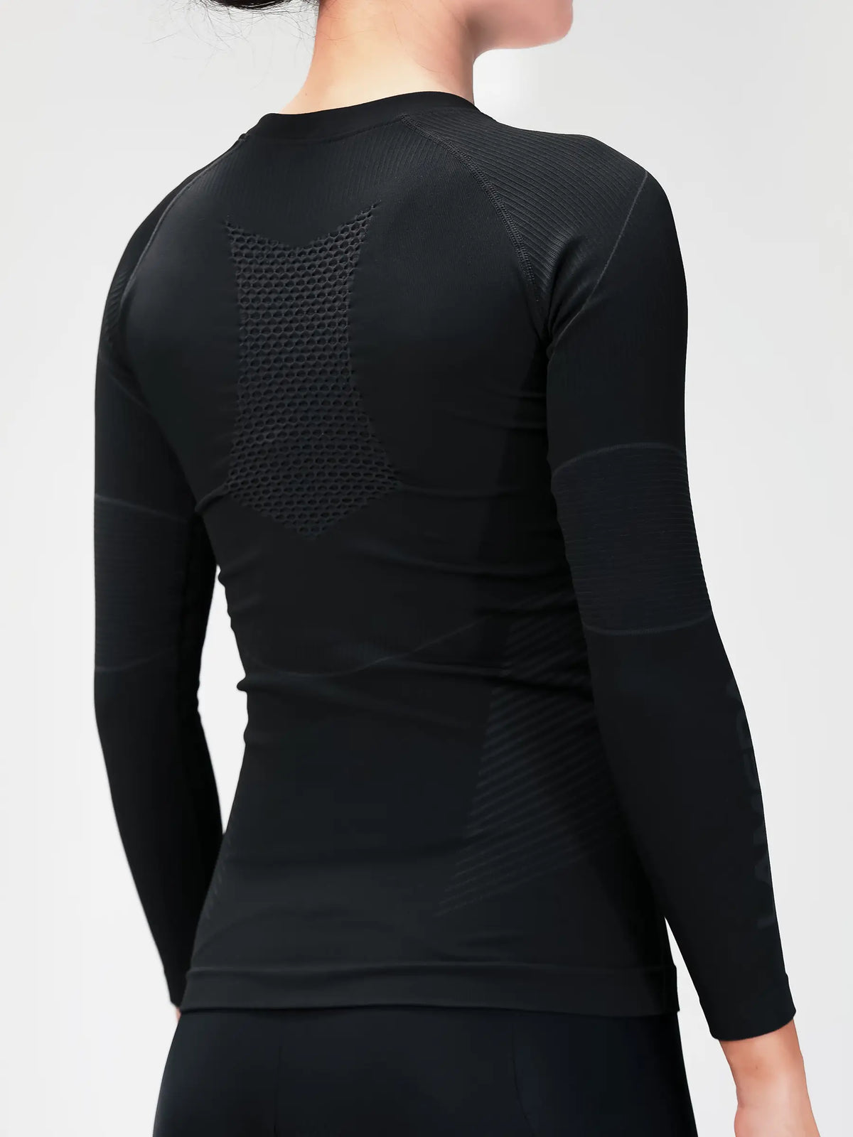 Woman’s compression top black back view with textured mesh panel made of bamboo charcoal fiber for cycling compression and muscle support