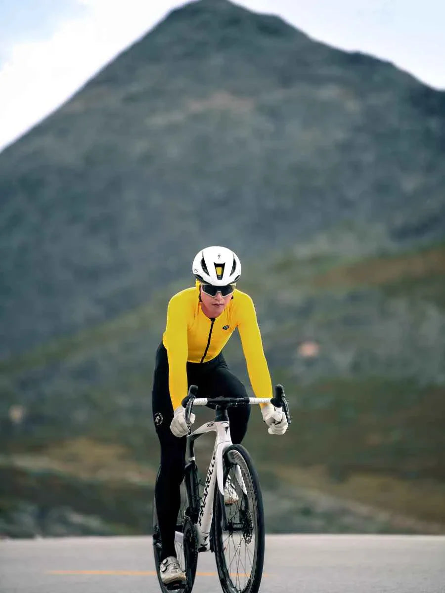 Athlete riding white bicycle wearing yellow polar night men’s fleeced thermal jersey and white helmet