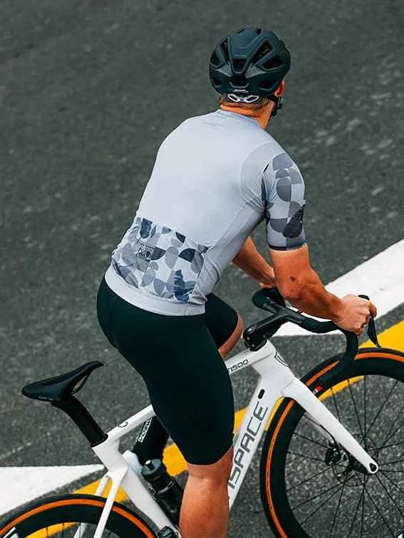 A sleek white bicycle with orange rims and black saddle beside a blue relaxed fit cycling jersey by ispace