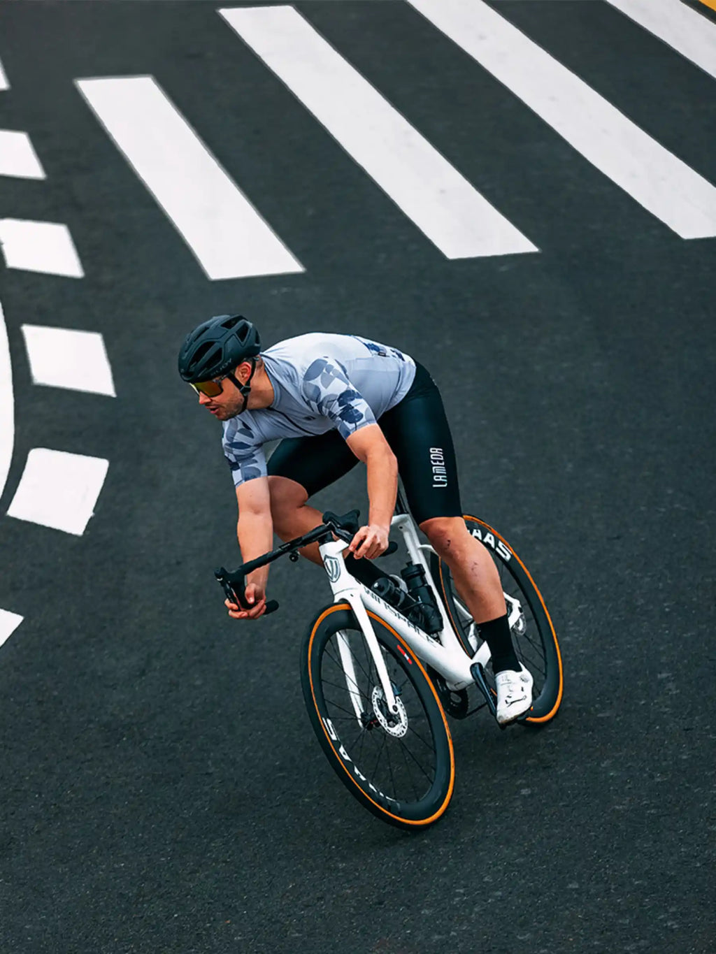 White road bike with orange-rimmed wheels and black handlebars next to a blue relaxed fit cycling jersey for men