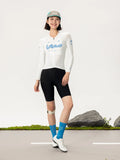 White long-sleeved lameda women’s cycling jersey with light blue branding paired with black shorts for women’s cycling
