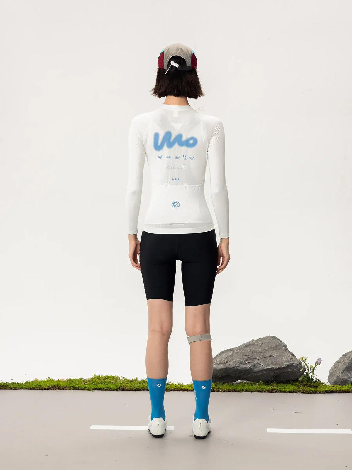 White long-sleeved lameda women’s cycling jersey with blue mo logo and subtle back graphic details for women’s cycling
